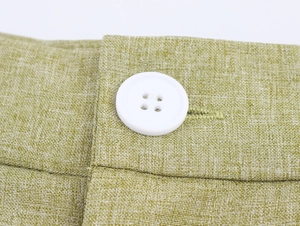 Close-up of light green linen fabric texture with a white four-hole button detail