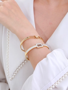 Close-up of golden butterfly and engraved Forever Love bangle set on model wrist