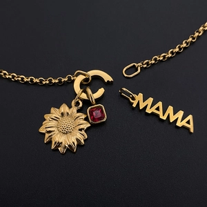 Vue détaillée macro du pendentif MAMA en acier titane doré avec breloques de tournesol