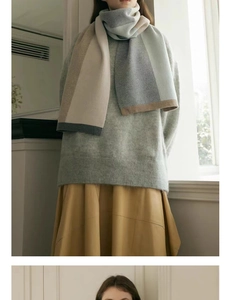 Detail of color-block knit scarf in beige and blue paired with a gray knit sweater