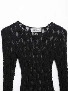 Macro shot of intricate floral lace texture and stitching on a black long sleeve top