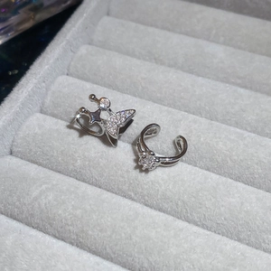 Detailed view of silver butterfly and star ear cuffs with cubic zirconia in a jewelry box