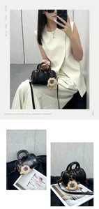 Detail of black pebbled leather Boston bag with plush lion charm and adjustable strap