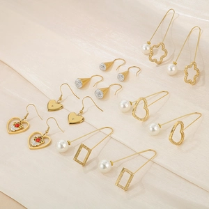 Detail shot of gold geometric earrings with pearls, crystals, and red gemstones