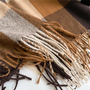 Close-up of brown and beige plaid pattern with fringe on soft knitted wool scarf