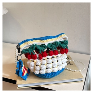 Detail of crochet cherry bucket bag featuring pearl strap and colorful knit texture