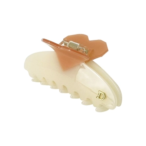 Detail view of heart-shaped cream and amber hair claw with gold metal letter D accent
