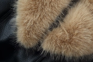 Detail shot of fluffy light brown faux fur trim on a high-quality black leather jacket