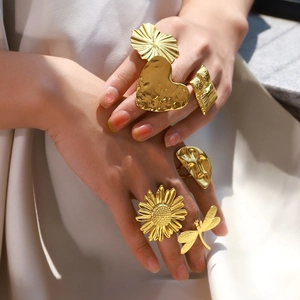 Detailed view of large gold statement rings with sun flower and heart textures on hands