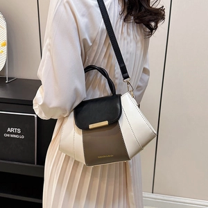 Contrast color crossbody bag in black and white PU leather worn by a model in interior