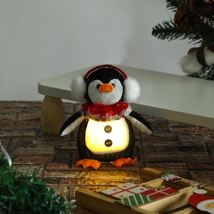 Close-up of plush Christmas penguin ornament with warm glowing belly on a festive backdrop