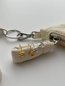 Detailed view of mushroom-shaped silver and gold earrings on textured leather background