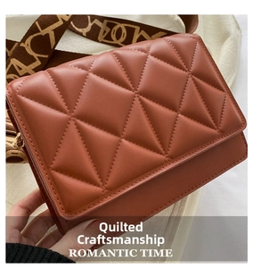 Detail of brown quilted crossbody bag featuring textured leather and a H-pattern fabric strap