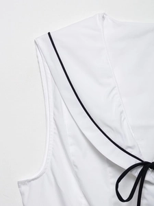 Détail d'un haut sans manches blanc avec col marin, liseré noir et décoration de nœud