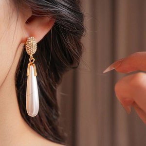 Elegant water drop pearl earrings with zircon inlay in gold finish on a model