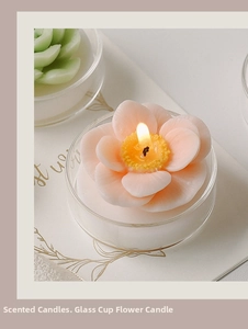 Close-up of pink flower scented candle in a glass jar with warm home decor lighting