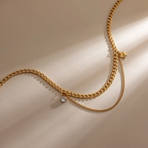 Detail of double-layer gold star necklace with round zircon charm and mixed link chains