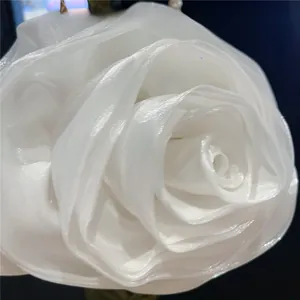 Macro detail of handcrafted white camellia fabric petals on elegant bridal evening bag