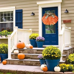 Pumpkin shaped autumn wreath with berries and pinecones hanging on a blue front door