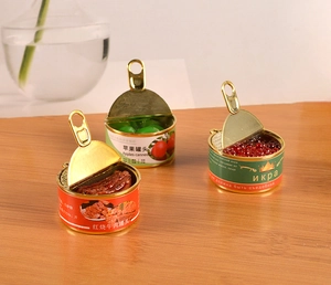 Close-up of miniature canned food models with realistic metal pull tabs on wood