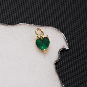 Macro shot of green heart-shaped crystal pendant with gold plating on a textured background