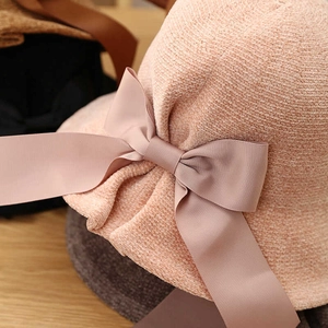 Detail of light pink knitted cloche hat featuring a large decorative side ribbon bow