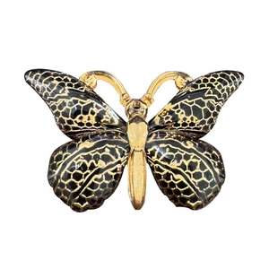 Detailed macro view of a golden butterfly pendant with black resin inlay and alloy base