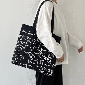 Close-up of black canvas tote bag with white cat illustration and 'biu biu' graphic print