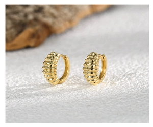 Macro detail of gold-plated croissant hoop earrings with elegant textured spiral ridges