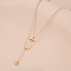 Détail du collier doré à deux rangs avec pendentifs abeille, papillon et perles