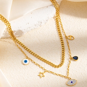 Détail d'un collier doré multicouche avec pendentifs œil et breloques en zircon sur pierre