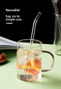 Close-up of curved glass straw in a glass with ice and fresh grapefruit slices