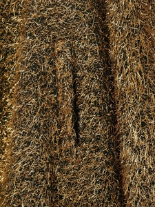 Dettaglio macro della trama con frange metalliche dorate sul tessuto del bomber