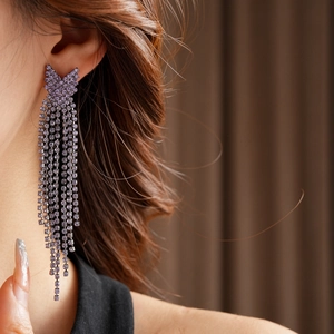Détail macro d'une boucle d'oreille à franges en strass violets portée avec éclat