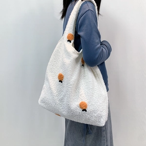 Detail of white plush tote bag showing soft sherpa texture and orange pompom accents