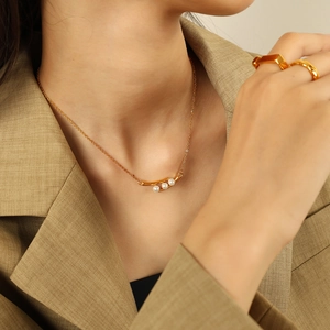 Élégant collier cosse de pois doré avec trois perles blanches porté par un mannequin