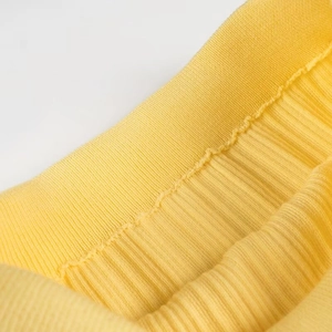 Gros plan sur le tissu en maille jaune montrant la texture côtelée et la couture détaillée