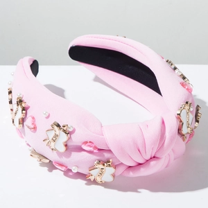 Détail du serre-tête tricoté rose avec perles blanches, cœurs et flèche de Cupidon