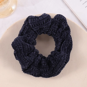 Macro shot of dark blue corduroy scrunchie texture on a beige plate for hair styling