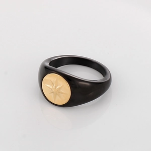 Detail of black titanium ring featuring a gold compass star design on a white background