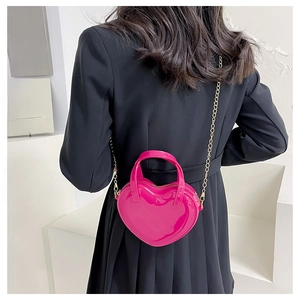 Detail view of pink heart-shaped patent leather crossbody bag with gold chain strap