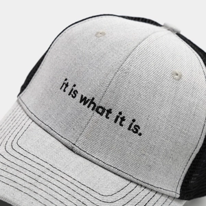 Detail of embroidered 'It is what it is' text on breathable mesh snapback truck cap