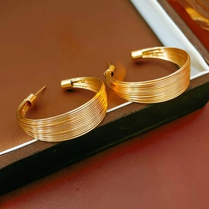 Detailansicht der goldfarbenen Lagen-Ohrringe auf einem braunen Schmuckständer