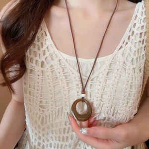 Close-up of vintage resin pendant necklace with wood beads on a crochet top