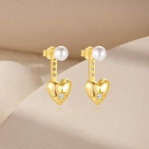 Macro detail of golden pearl heart earrings with sparkling inlaid gemstone accents