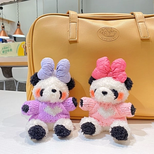Gros plan de porte-clés panda en peluche avec pulls tricotés et nœuds sur un sac