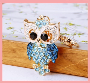 Macro shot of owl keychain featuring gradient blue rhinestones on golden metal base