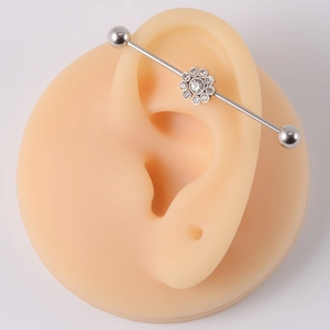 Detailed view of silver stainless steel industrial barbell with small flower design