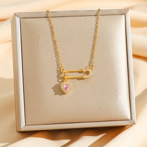 Chic gold safety pin necklace featuring a pink heart zircon on a premium jewelry box