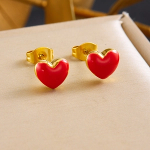 Elegant gold heart earrings with red enamel inlay shown on a soft jewelry display box